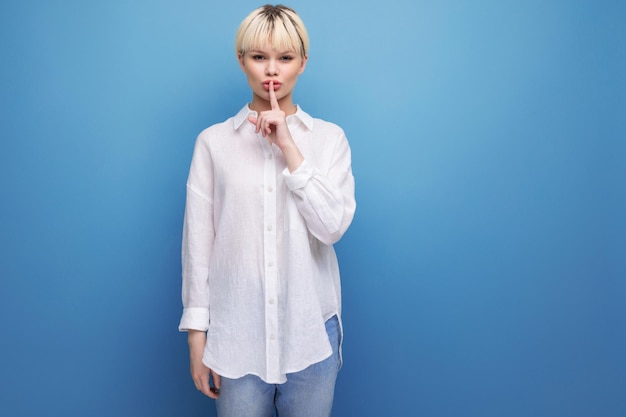 Photo young calm pretty blonde businesswoman in a white shirt keeps a secret on the background with copy