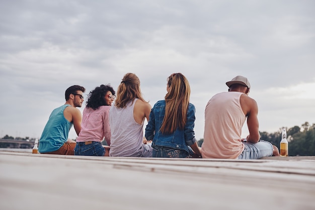 Young and carefree. Rear view of young people in casual wear smiling and talking 