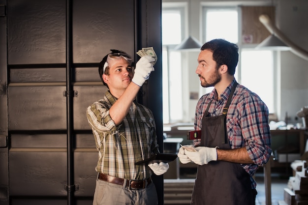 Young carpenter gets his money for work in workshop carpentry