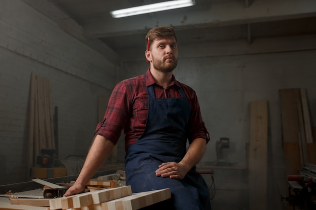 Young carpenter with an apron in his workshop