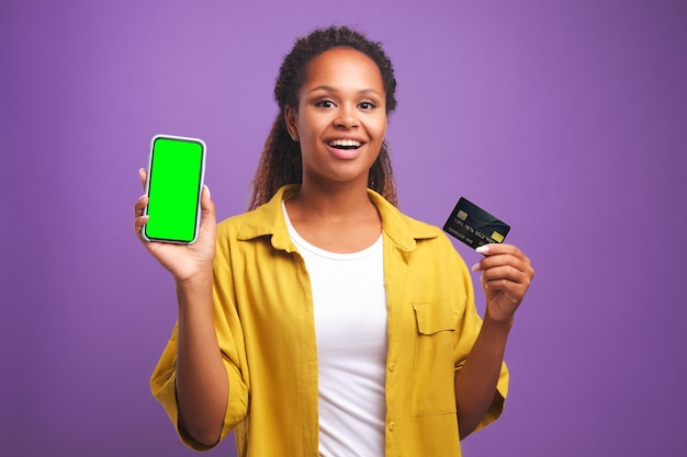 Young casual african american woman holding green screen phone and credit card