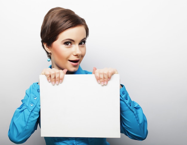 Young casual woman happy holding blank sign 