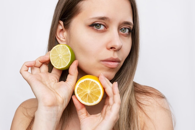 A young caucasian attractive blonde woman holding a halfs a lime and a lemon in her hands