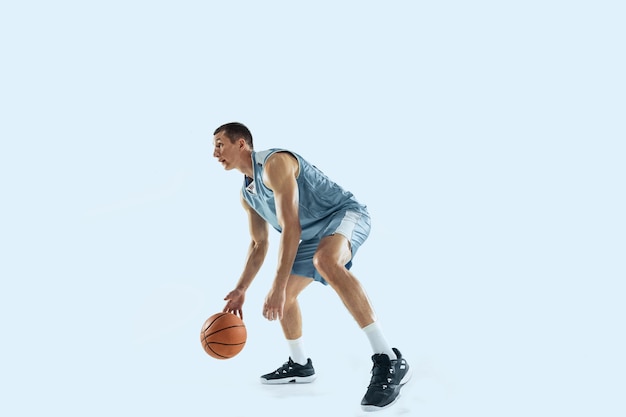 Young caucasian basketball player against white studio background