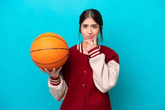 Young caucasian basketball player woman isolated on blue background having doubts and thinking