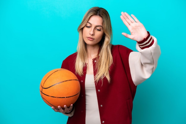 Young caucasian basketball player woman isolated on blue background making stop gesture and disappointed