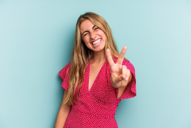 Young caucasian blonde woman isolated on blue background  showing number two with fingers.