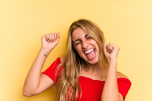 Young caucasian blonde woman isolated on yellow background  dancing and having fun.