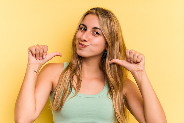 Young caucasian blonde woman isolated on yellow background  feels proud and self confident, example to follow.