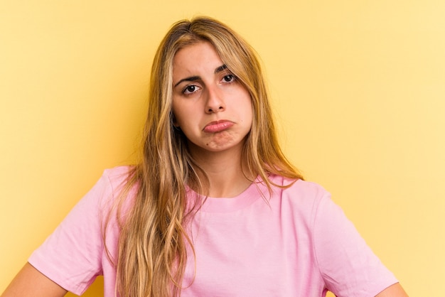 Young caucasian blonde woman isolated on yellow background  sad, serious face, feeling miserable and displeased.