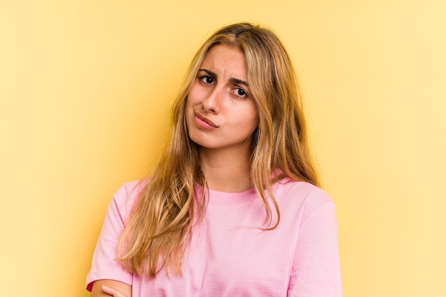 Young caucasian blonde woman isolated on yellow background  unhappy looking in camera with sarcastic expression.