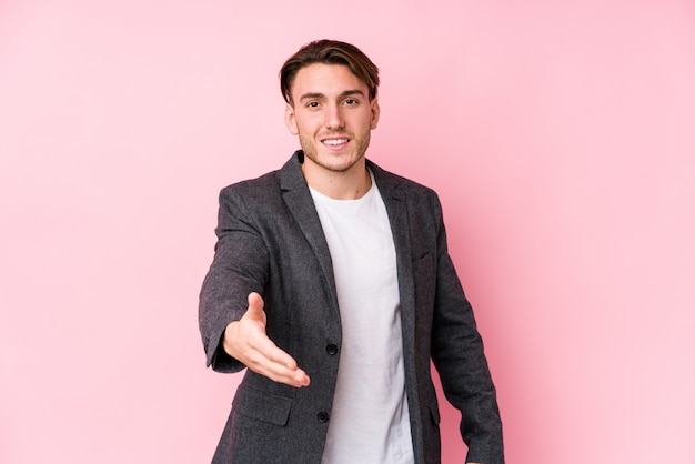 Young caucasian business man posing isolated stretching hand in greeting gesture.