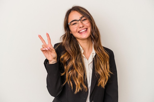 Young caucasian business woman isolated on white background joyful and carefree showing a peace symbol with fingers.