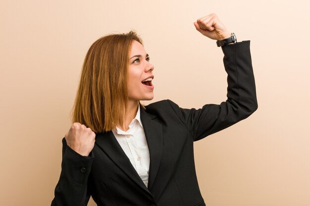 Photo young caucasian business woman raising her fist after a victory, winner concept.