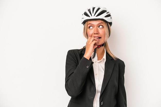 Young caucasian business woman wearing a bike helmet isolated on white background relaxed thinking about something looking at a copy space.