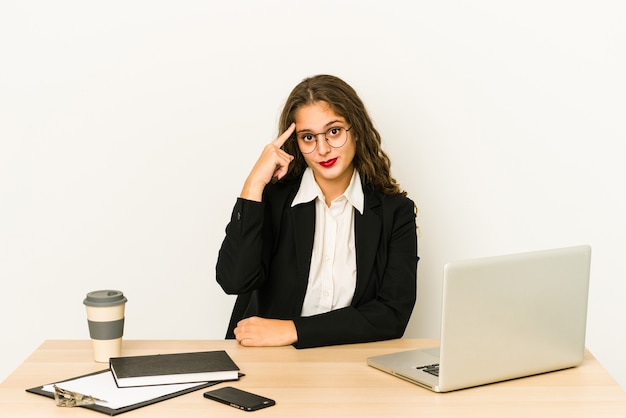 Photo young caucasian business woman working on her desktop isolated pointing temple with finger, thinking, focused on a task.