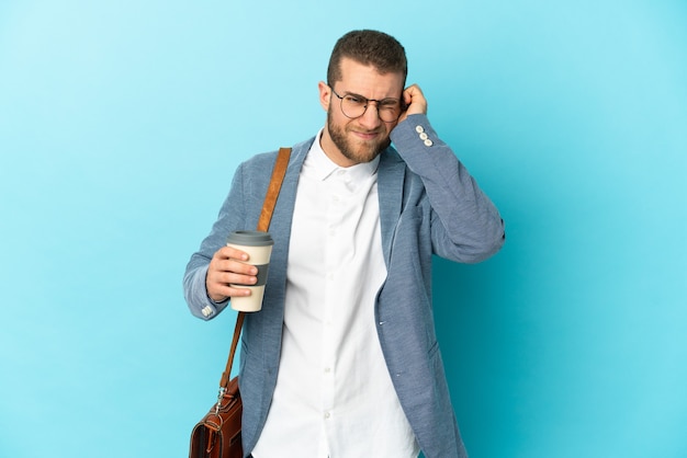 Young caucasian businessman isolated on blue wall frustrated and covering ears