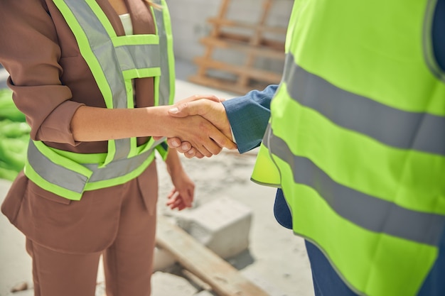 a young Caucasian businesswoman and a male worker greeting each other outside