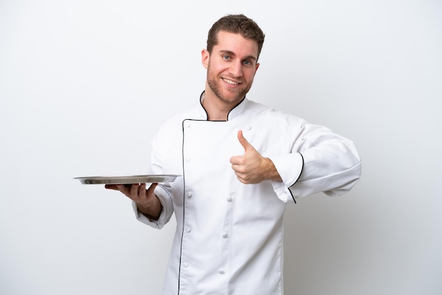 Young caucasian chef with tray isolated on white background giving a thumbs up gesture