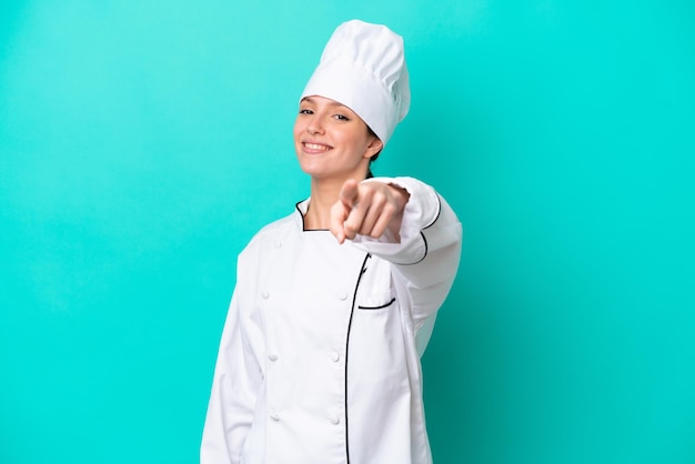 Young caucasian chef woman isolated on blue background points finger at you with a confident expression