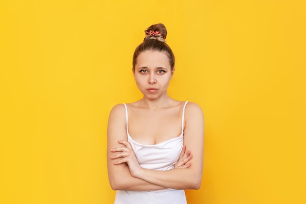 A young caucasian confident slim blonde woman crossing her arms over her stomach on yellow color