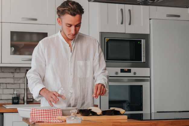 Young Caucasian cook at home putting salt to the eggplants so that they start to get mushy