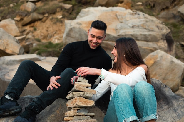 Young caucasian couple building a rock tower on the beach