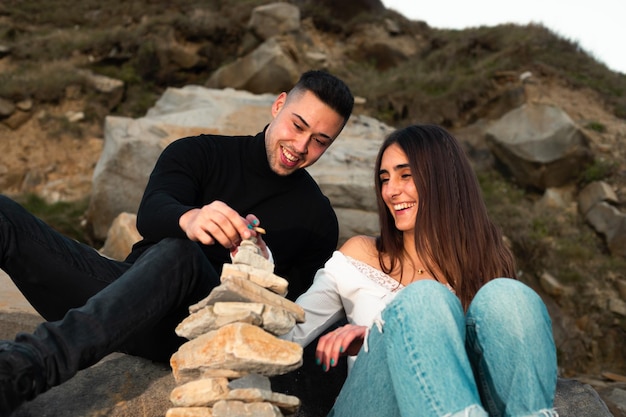 Young caucasian couple building a rock tower on the beach