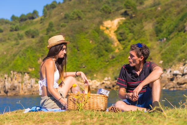 A young Caucasian couple on the picnic in the mountains by the sea enjoying the heat