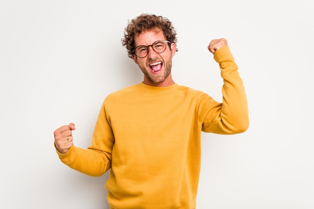 Photo young caucasian curly hair man isolated on white background cheering carefree