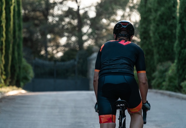 Young caucasian cyclist on his back riding his bike surrounded by trees