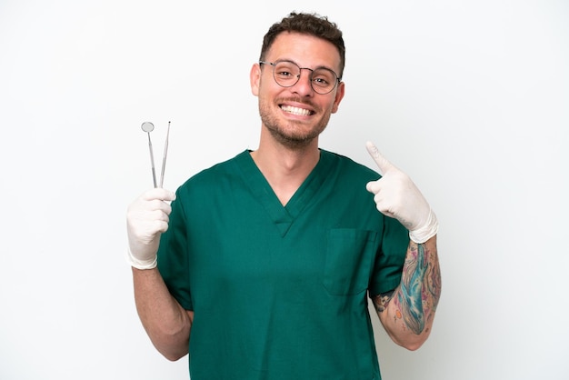 Young caucasian dentist man isolated on white background giving a thumbs up gesture