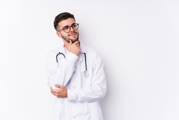 Young caucasian doctor man isolated looking sideways with doubtful and skeptical expression.