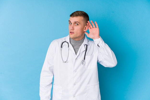 Young caucasian doctor man trying to listening a gossip.