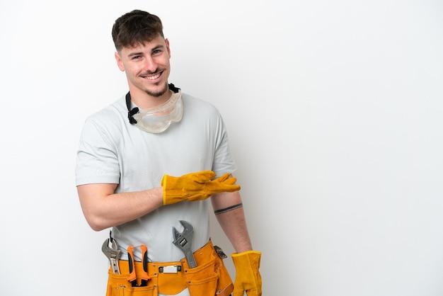 Young caucasian electrician man isolated on white background presenting an idea while looking smiling towards