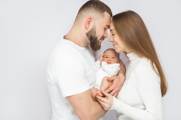 Young Caucasian family with small daughter pose relax on floor in living room smiling little girl kid hug embrace parents show love and gratitude rest at home together