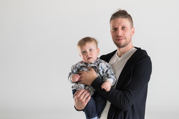 Young caucasian father holding a baby in his arms on a white background