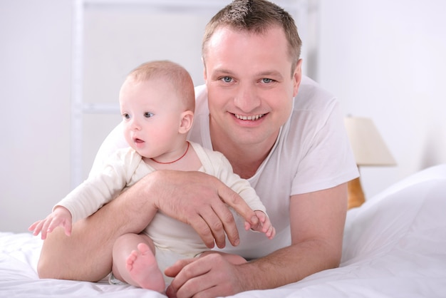 Young Caucasian father playing with baby son at home.