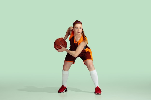 Young caucasian female basketball player against mint colored studio background