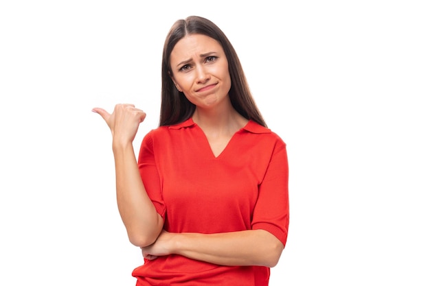 Young caucasian female model with black straight hair dressed in a red tshirt with a doubt points a