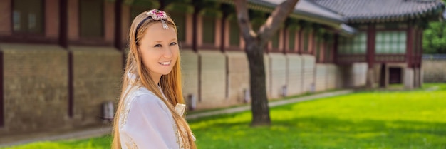 Young caucasian female tourist in hanbok national korean dress Travel to Korea concept National Korean clothing Entertainment for tourists trying on national Korean clothing BANNER LONG FORMAT