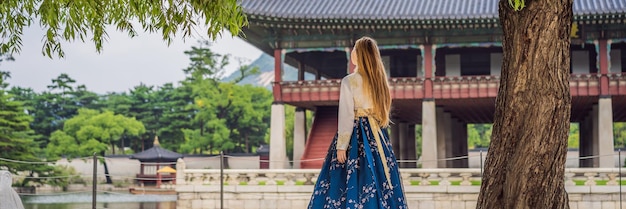 Young caucasian female tourist in hanbok national korean dress Travel to Korea concept National Korean clothing Entertainment for tourists trying on national Korean clothing BANNER LONG FORMAT