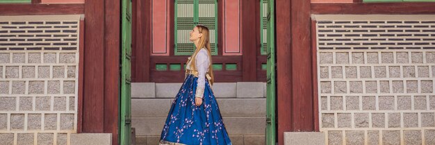 Young caucasian female tourist in hanbok national korean dress Travel to Korea concept National Korean clothing Entertainment for tourists trying on national Korean clothing BANNER LONG FORMAT