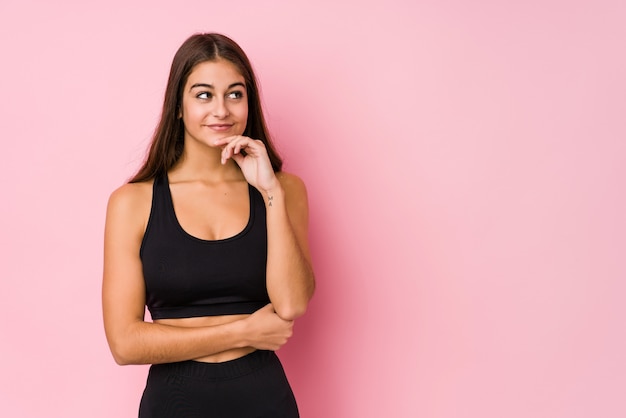 Young caucasian fitness woman doing sport isolated looking sideways with doubtful and skeptical expression.