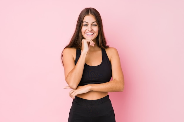 Young caucasian fitness woman doing sport isolated smiling happy and confident, touching chin with hand.