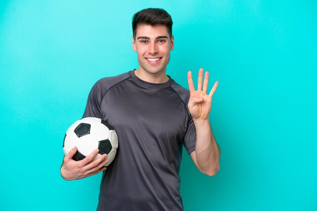 Young caucasian football player man isolated on blue background happy and counting four with fingers