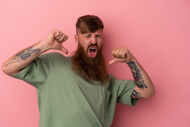 Young caucasian ginger man with long beard isolated on pink background feels proud and self confident, example to follow.