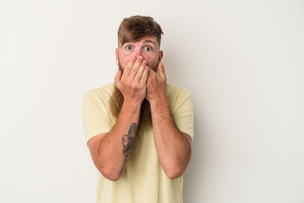 Young caucasian ginger man with long beard isolated on white background shocked, covering mouth with hands, anxious to discover something new.