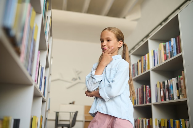 Young Caucasian girl concentrated on choosing textbooks