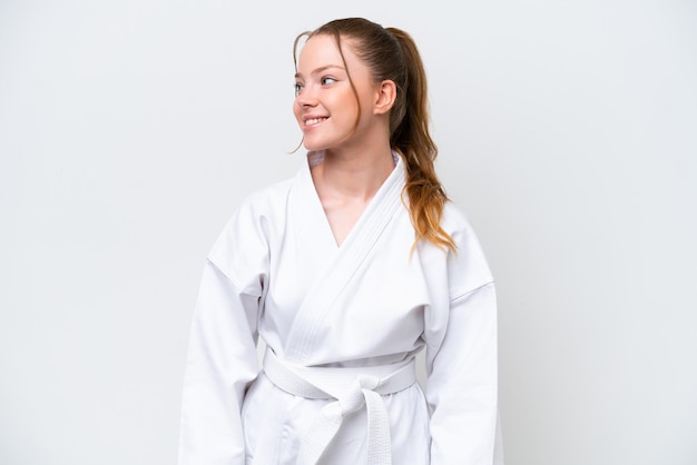 Young caucasian girl doing karate isolated on white background looking side